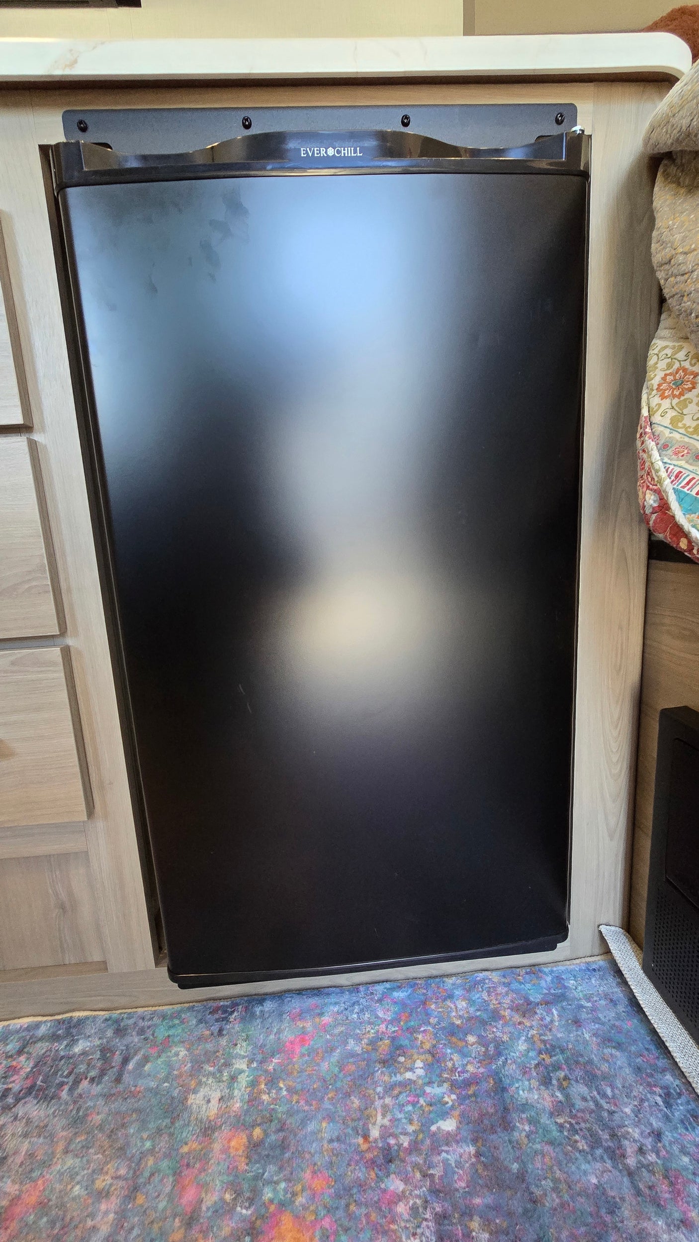Compact black EVERCHILL RV refrigerator for your next rv rental adventure. Integrated into a cozy vehicle interior.