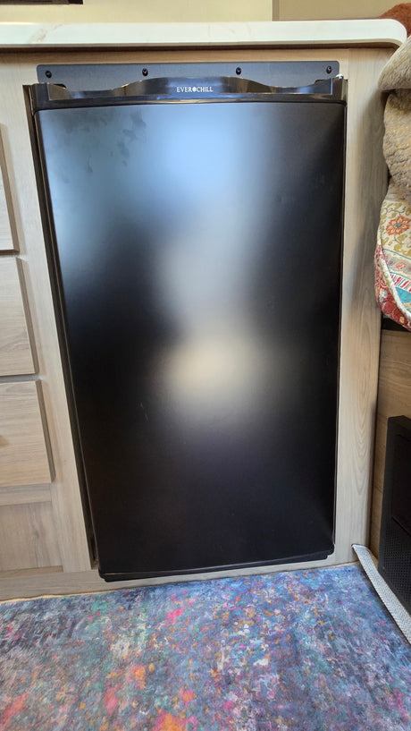 Compact black EVERCHILL RV refrigerator for your next rv rental adventure. Integrated into a cozy vehicle interior.