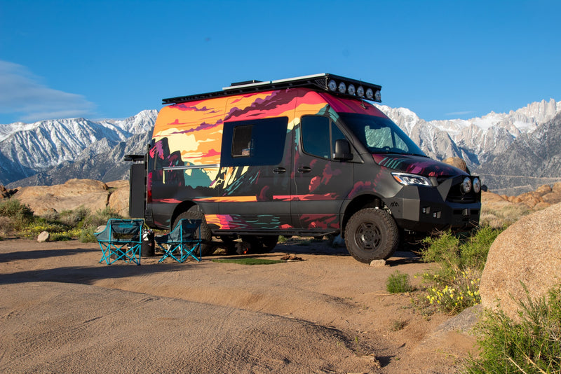  set against mountains in a desert camp.|Scenic rv rental: a custom camper van with a fire — photo 16