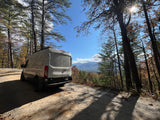 White van on a dirt road, offering a scenic mountain view—ideal for an RV rental adventure.