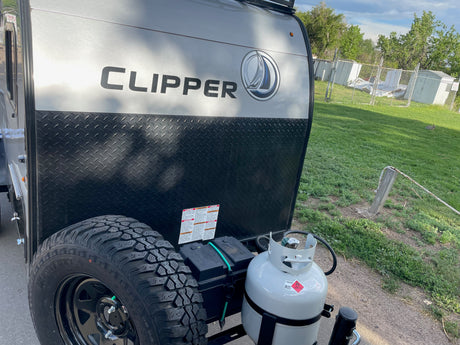 Front of a Clipper RV rental, featuring its spare tire, propane tank, and power system. Perfect for outdoor adventures.