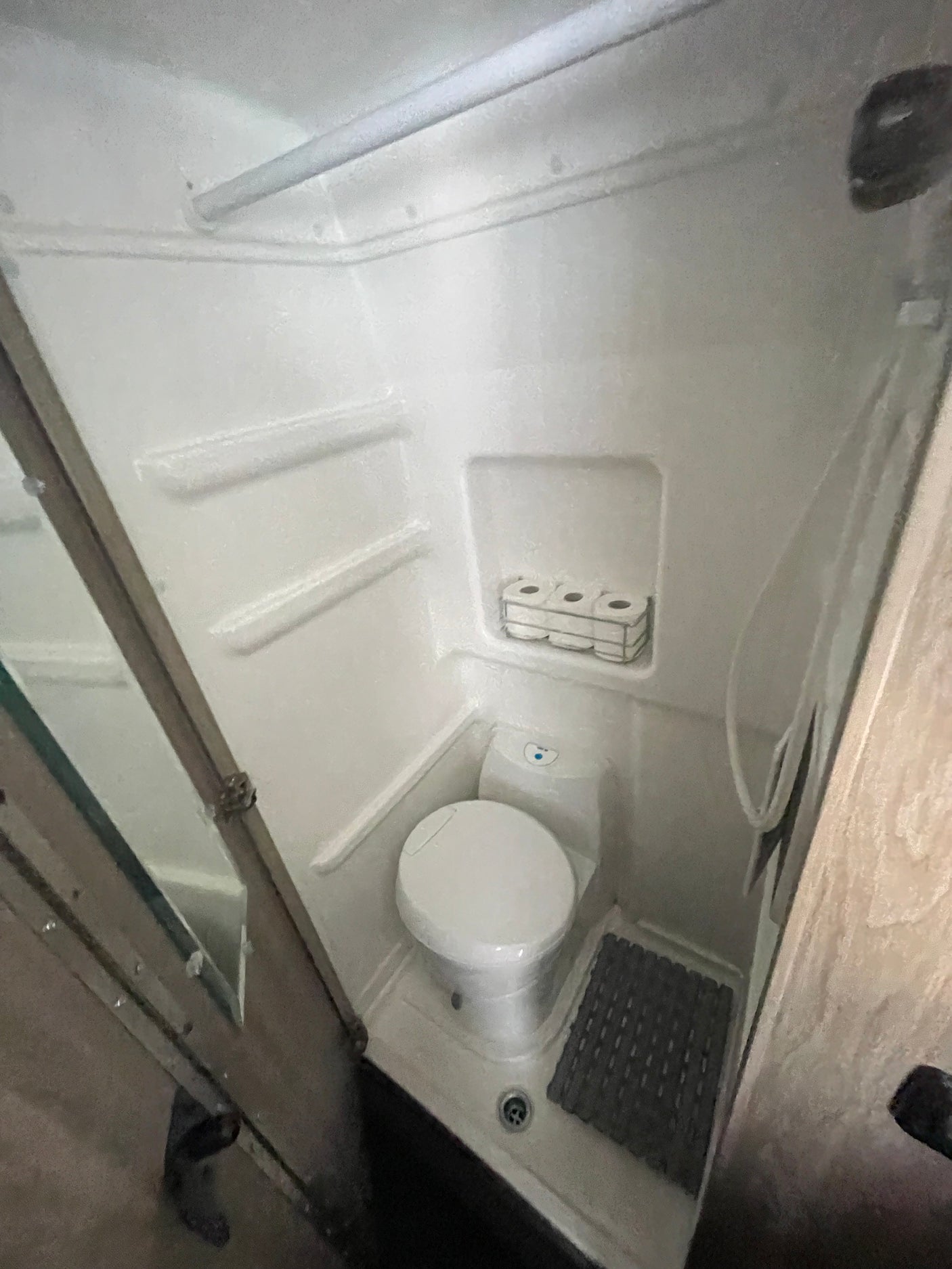 This compact RV rental wet bath combines a toilet, shower, and handy toilet paper storage, optimizing space for travel.