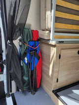 RV rental's compact interior: clever storage of camping gear next to a convertible bed and cabinet.