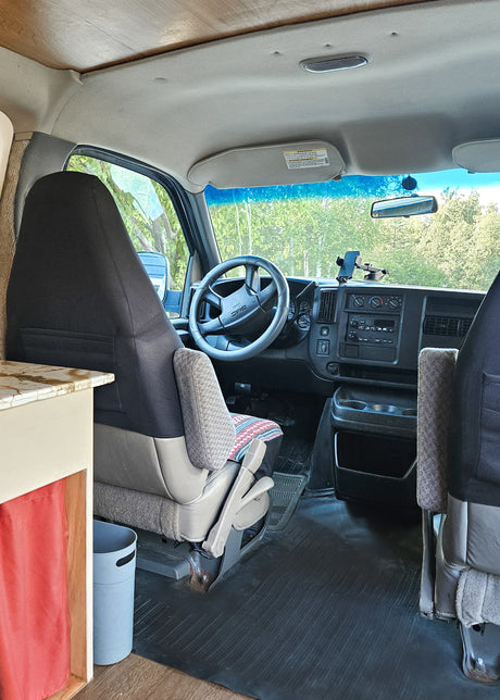 Inside this RV rental van conversion: driver's area with dashboard, steering, and a custom wood ceiling. Ready for adventure!