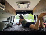 Enjoy a serene escape! A person reads in a cozy RV rental, overlooking a peaceful lake.