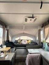 Cozy RV rental interior with a comfy bed, kitchen, and dining area, offering serene views of the outdoors.