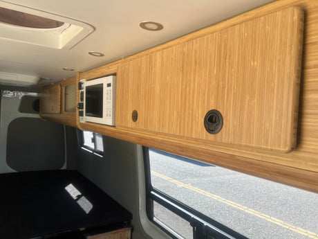 Inside an rv rental: custom bamboo cabinetry, integrated microwave, and ceiling vent for comfortable travel.