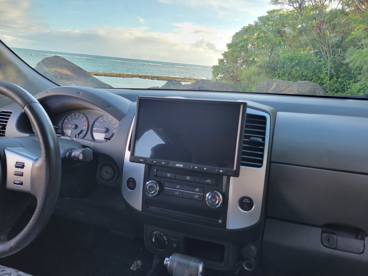 Dashboard of a rental vehicle overlooking the ocean, featuring an ATOTO screen. Great for adventures like an RV rental.
