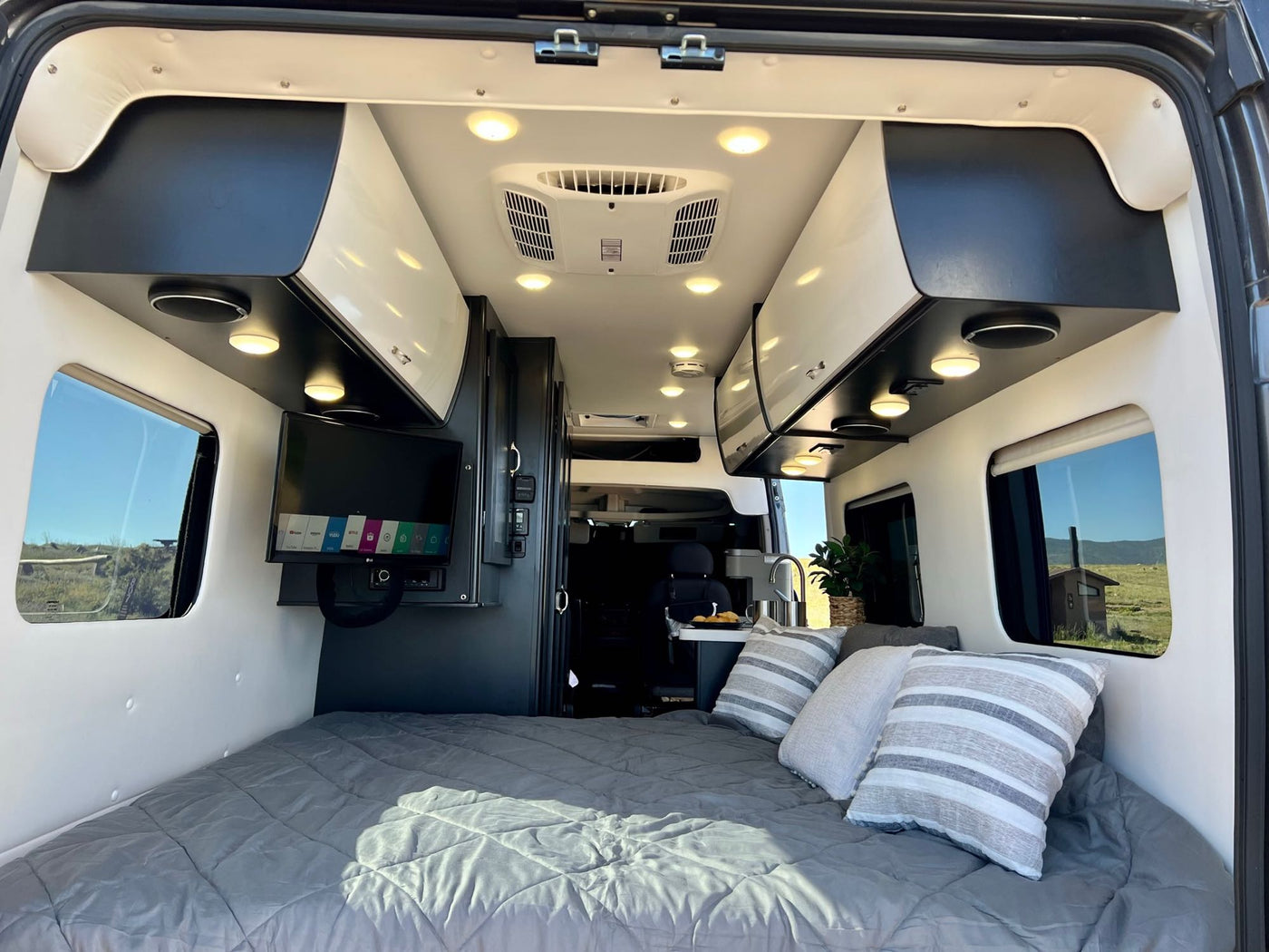  and overhead lighting.|Spacious RV rental interior featuring a modern kitchen area with a sink and stove — photo 15