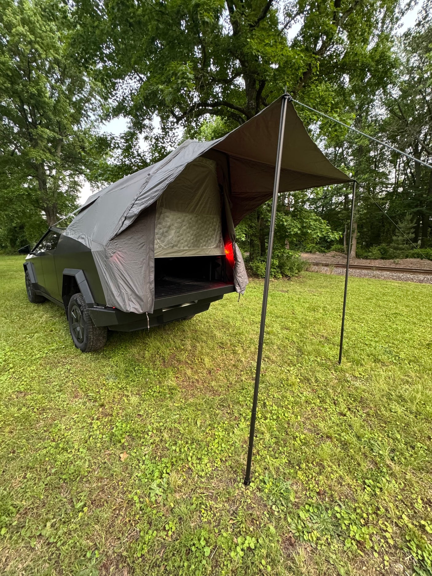  parked on grass. A unique RV rental option for outdoor adventure.|Innovative Cybertruck camping setup