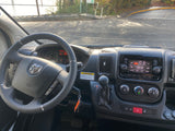 Inside an RV rental van: dashboard, steering wheel, and console controls. The vehicle is parked, ready for adventure.