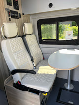 RV rental interior features comfortable quilted seats, a dining table, and control panels. Ready for your next adventure!