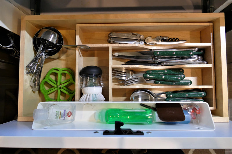 Organized kitchen & camping essentials for your RV rental: cutlery, measuring tools, multi-tool, and cleaning supplies neatly stored. — photo 13