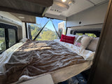 Enjoy a comfy bed in this RV rental's bedroom, complete with holiday decor and scenic views from the open rear doors.