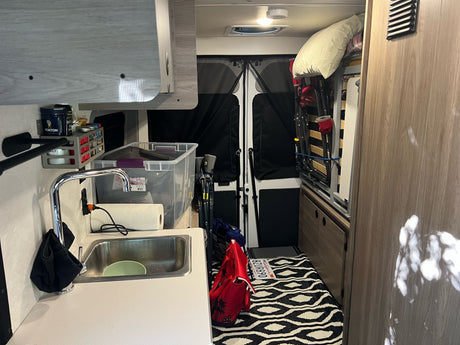 Compact RV rental interior with kitchenette, bed, and smart storage solutions for travel. Ideal for a camper van adventure.