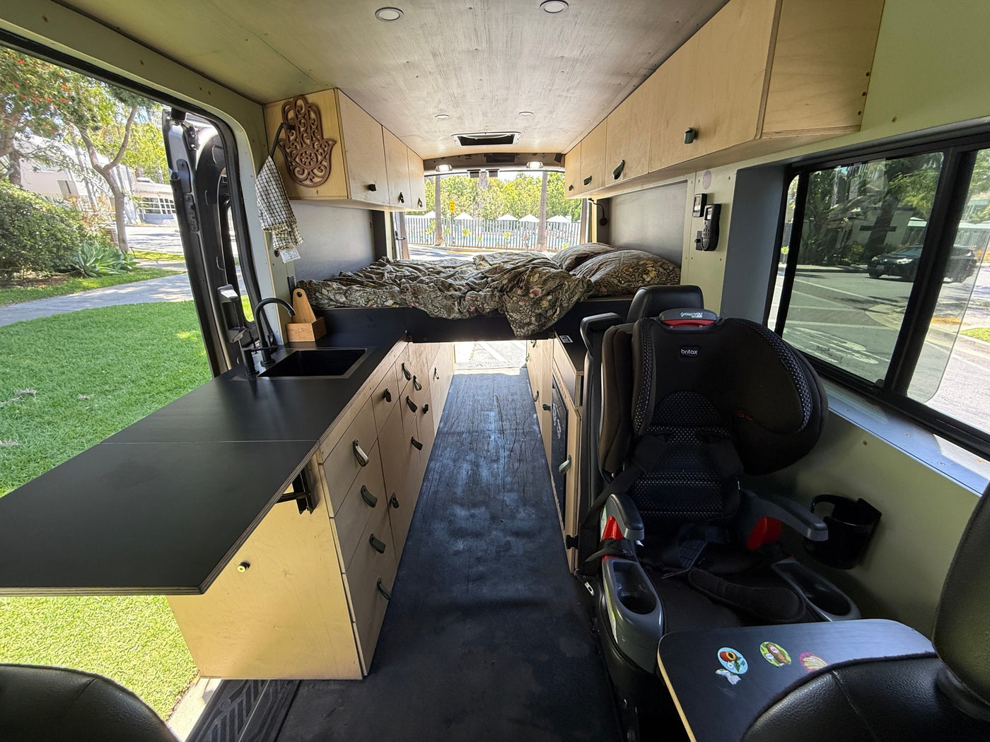 Cozy RV rental interior, featuring a custom kitchen on the left, a bed at the back, and a child seat on the right. — photo 10