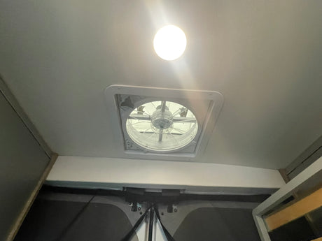 Interior of an rv rental showing a bright ceiling light and a functional roof vent fan, indicating comfort features.