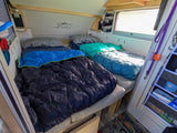 Cozy rv rental interior with two beds, sleeping bags, an adventure wall decal, and pet-friendly amenities like a leash.