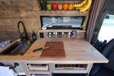 Custom RV rental kitchen with sink, butcher block counters, and smart storage. Perfect for your next adventure!