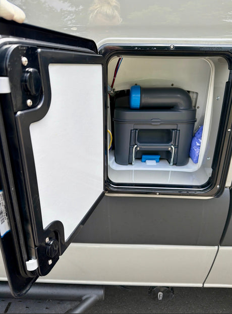 rv rental: View into an open external RV compartment, revealing a removable cassette toilet system for waste disposal.