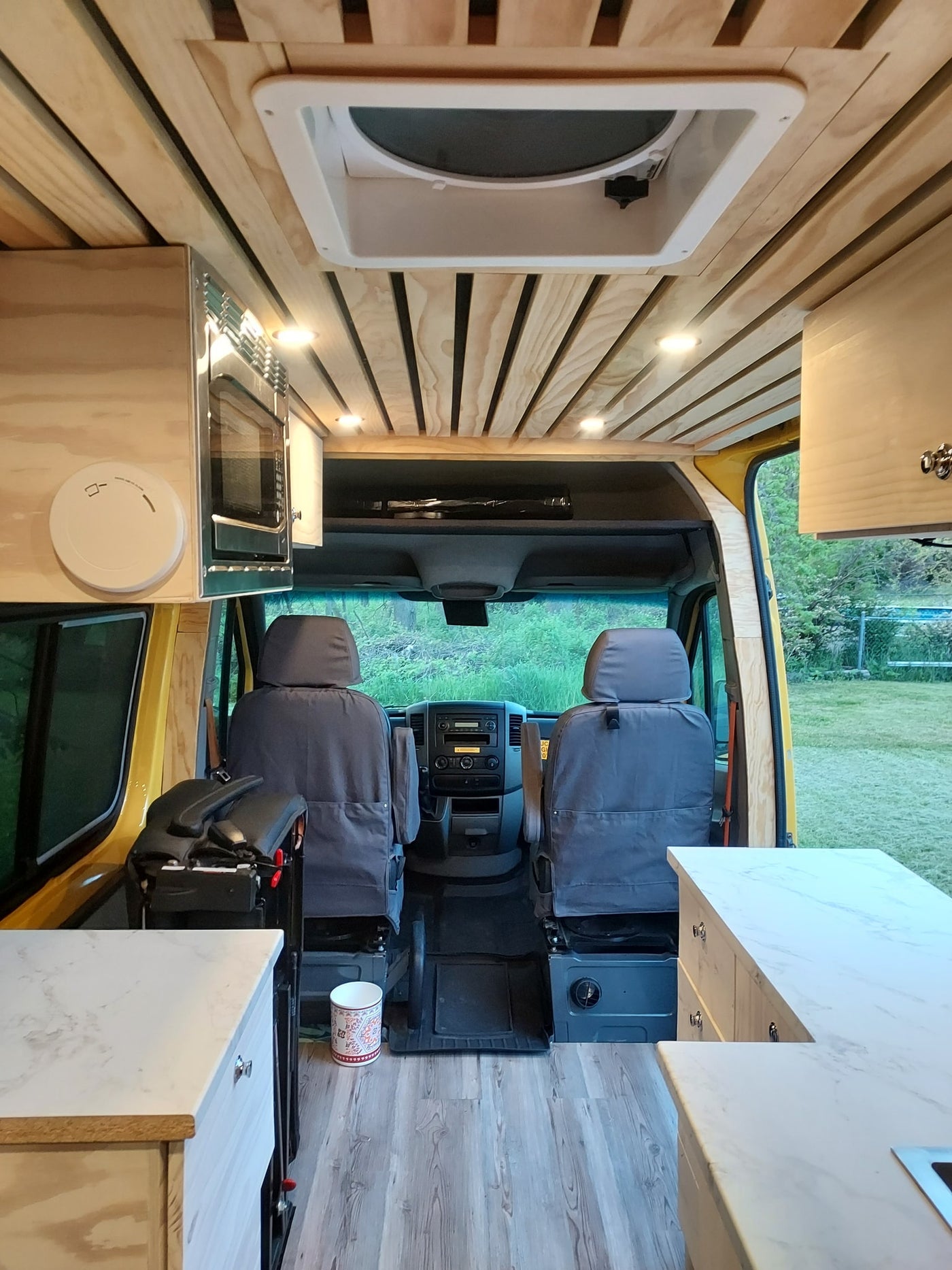  a house and black dog nearby. RV rental ready!|Yellow RV rental van parked on grass with a blue shower tent and red canopy setup