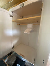 Compact RV rental wardrobe with shelf, hanging rod, hangers, and a pull-out drawer for organized storage.