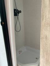 RV rental: Compact camper shower with a flexible hose and white basin, a functional space for travelers.