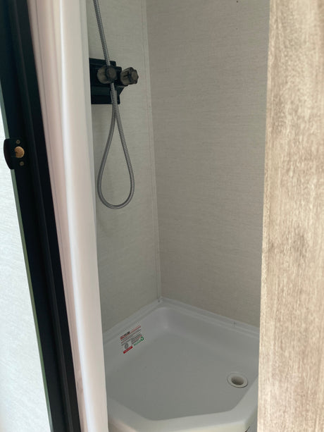 RV rental: Compact camper shower with a flexible hose and white basin, a functional space for travelers.