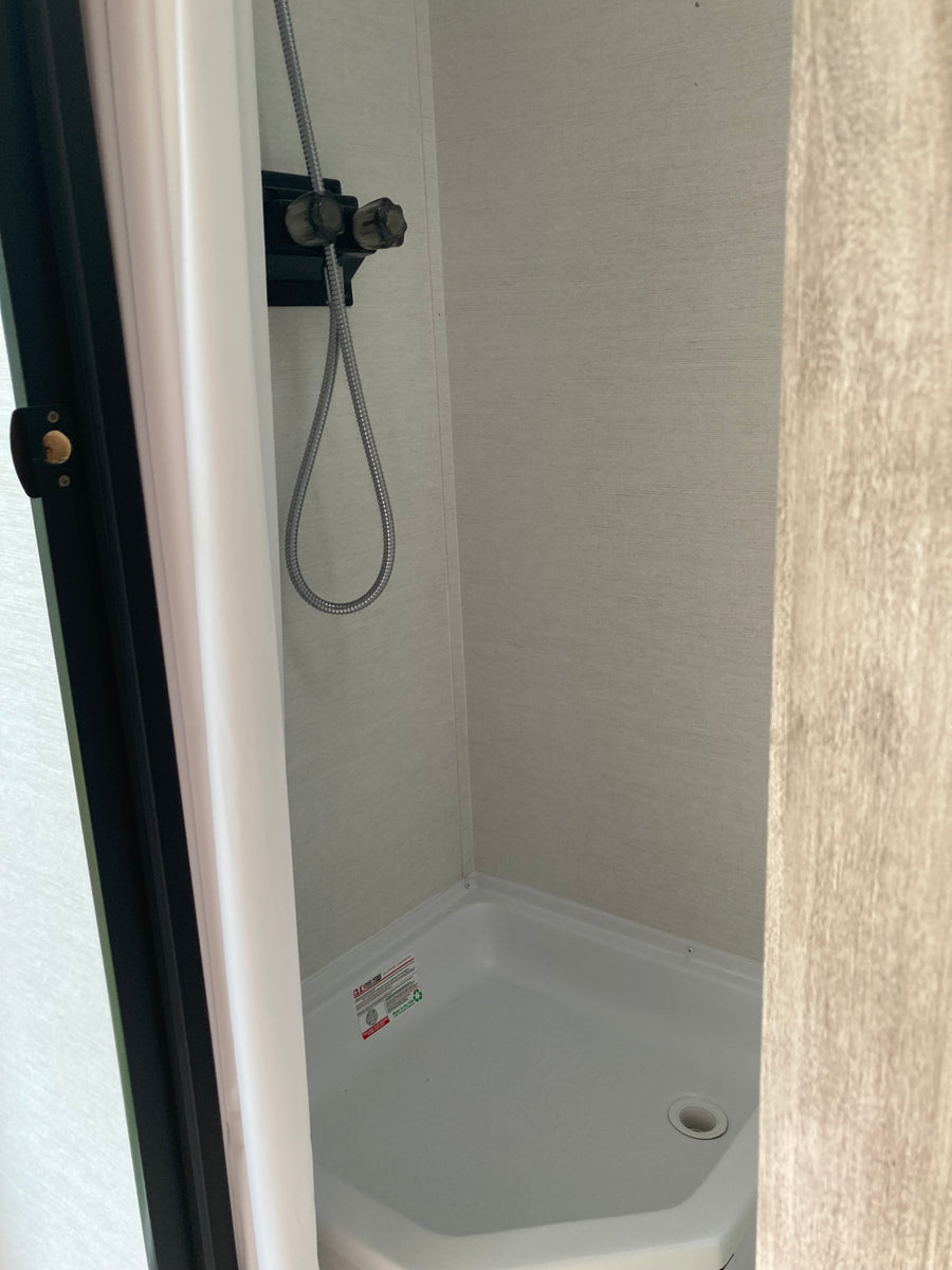 RV rental: Compact camper shower with a flexible hose and white basin, a functional space for travelers.