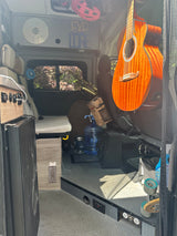 Inside an RV rental camper van: an acoustic guitar, saxophone, and adventure gear fill the custom-built interior.