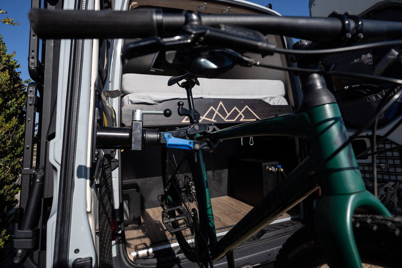 Green mountain bike neatly stored in a custom RV rental interior, featuring a cozy bed and utility storage.