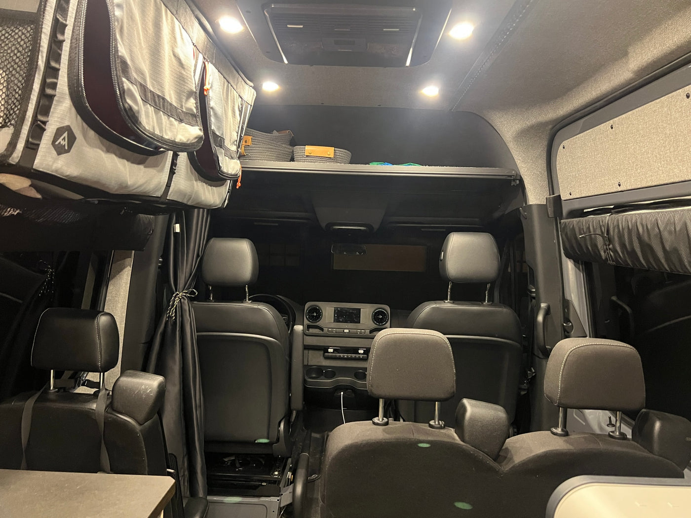 Spacious, organized interior of an rv rental camper van, featuring comfortable seating and overhead storage. — photo 12