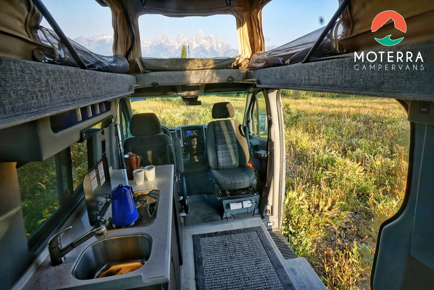 This RV rental offers a spacious interior: kitchen, swivel seats, pop-top bed, and majestic mountain views. — photo 11