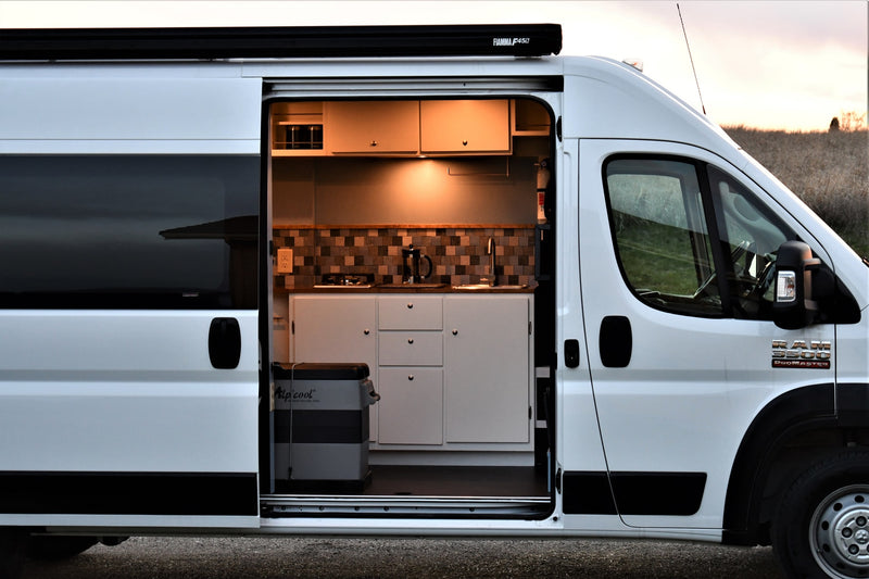 White camper van rv rental with open side door revealing custom kitchen, perfect for mobile living adventures. — photo 1