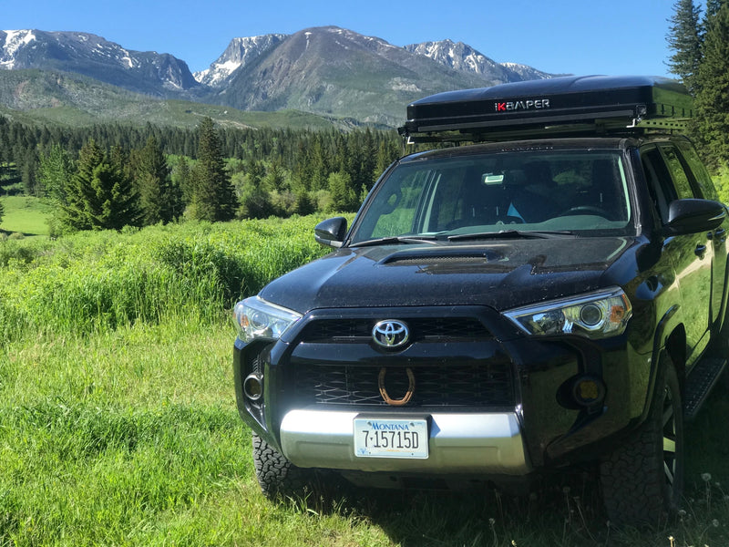 Black 4Runner with rooftop tent parked in a green mountain landscape. Explore nature; a rugged RV rental alternative for adventure. — photo 9