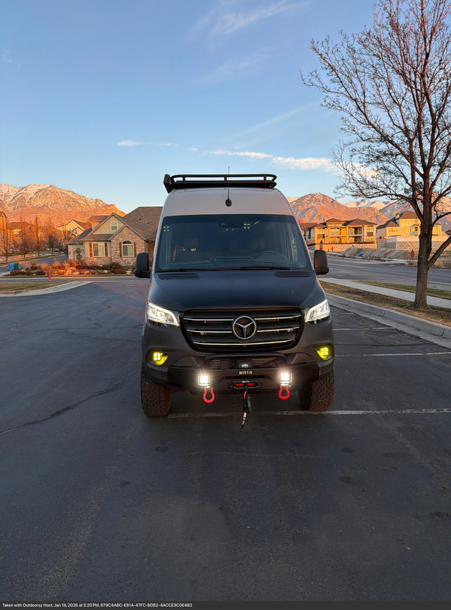 Get ready for adventure! This rugged Mercedes-Benz Sprinter rv rental, equipped with off-road gear, is parked with snowy mountain views at sunset.