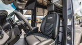 RV rental interior: luxurious black leather seats with diamond stitching, '2NORTH' logo, steering wheel, and cabin storage.
