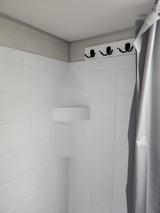 RV rental shower interior with white molded walls, corner shelf, and hooks for convenience. Clean & compact.