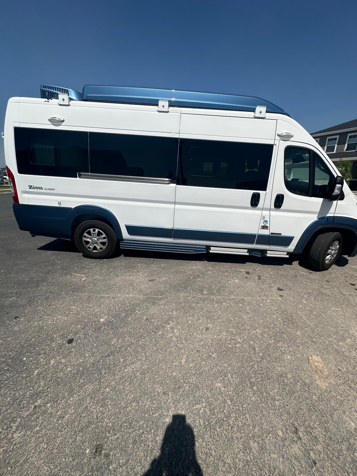 Side view of a white & blue Zion Slumber camper van, ideal for an RV rental road trip adventure.
