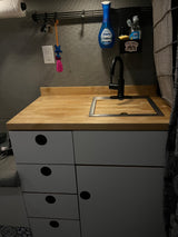 RV rental kitchen: compact sink, wood counter, and storage with essentials like Dawn soap.
