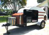 Charming teardrop camper, a perfect rv rental, with open doors revealing its cozy interior and a front cooler.