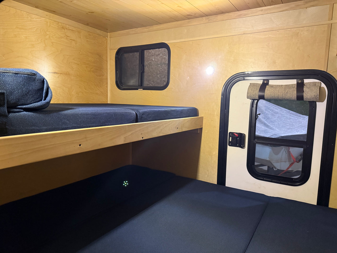 rv rental interior: wooden bunk beds with dark mattresses and windows offer a compact, cozy sleeping space for adventures.