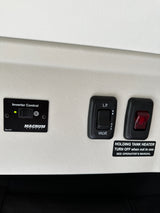 RV rental interior with switches for holding tank heater, LP gas valve, and inverter control.
