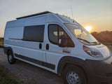 White Ram ProMaster camper van, a great RV rental for sunset road trips, parked on a rural gravel road.