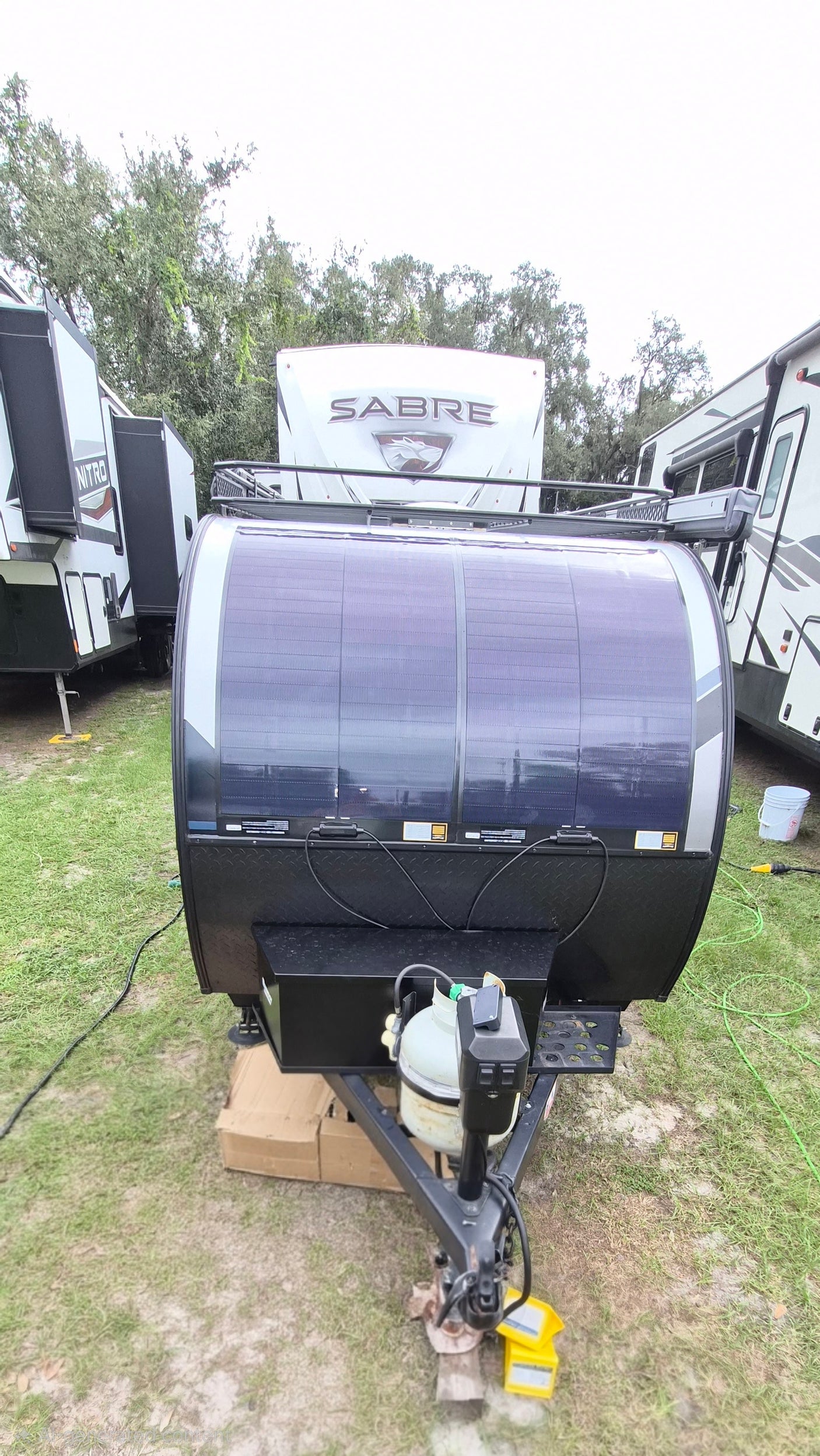 Front view of a teardrop RV rental featuring a large solar array, propane tanks, and a utility hitch.