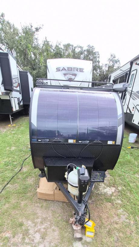 Front view of a teardrop RV rental featuring a large solar array, propane tanks, and a utility hitch.