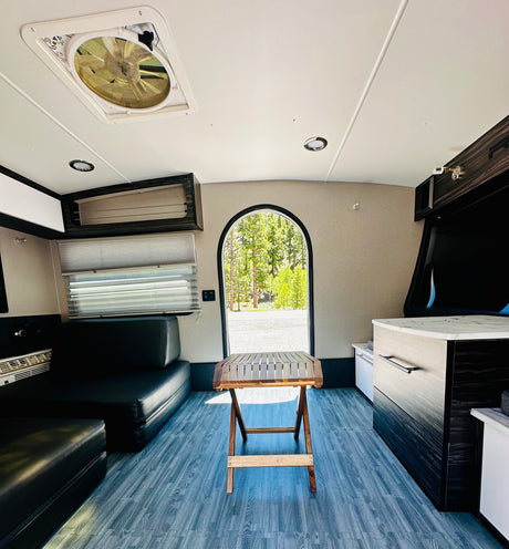 Explore this rv rental's interior: modern design with comfortable seating, a folding table, and a view to the outdoors.