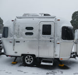 Snow-covered silver Airstream travel trailer, ideal for a cozy winter rv rental getaway.