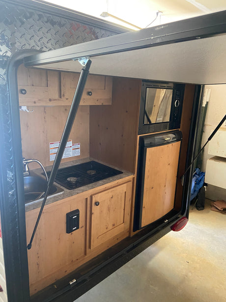 Explore this compact RV rental with a fully equipped rear outdoor kitchen: sink, stovetop, microwave, and fridge.