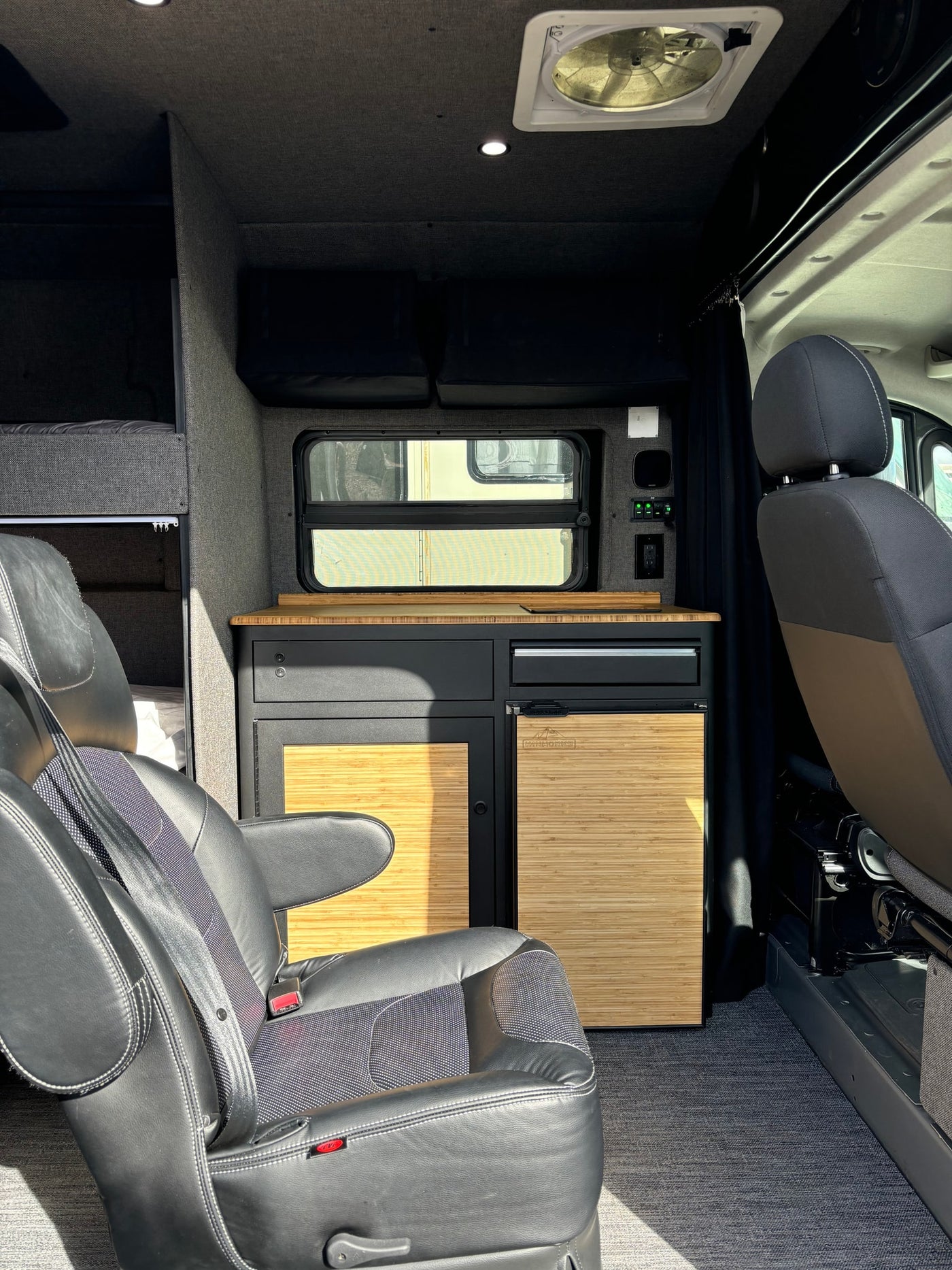Inside a compact RV rental: featuring a well-equipped kitchenette, comfortable bunk beds, and swivel front seats in a modern camper. — photo 3
